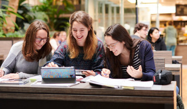 Drei Studentinnen sitzen in der Osthalle des Uniklinikums und arbeiten gemeinsam an einer Präsentation