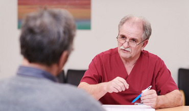 Ein Krankenpfleger im Gespräche mit einem Patienten.