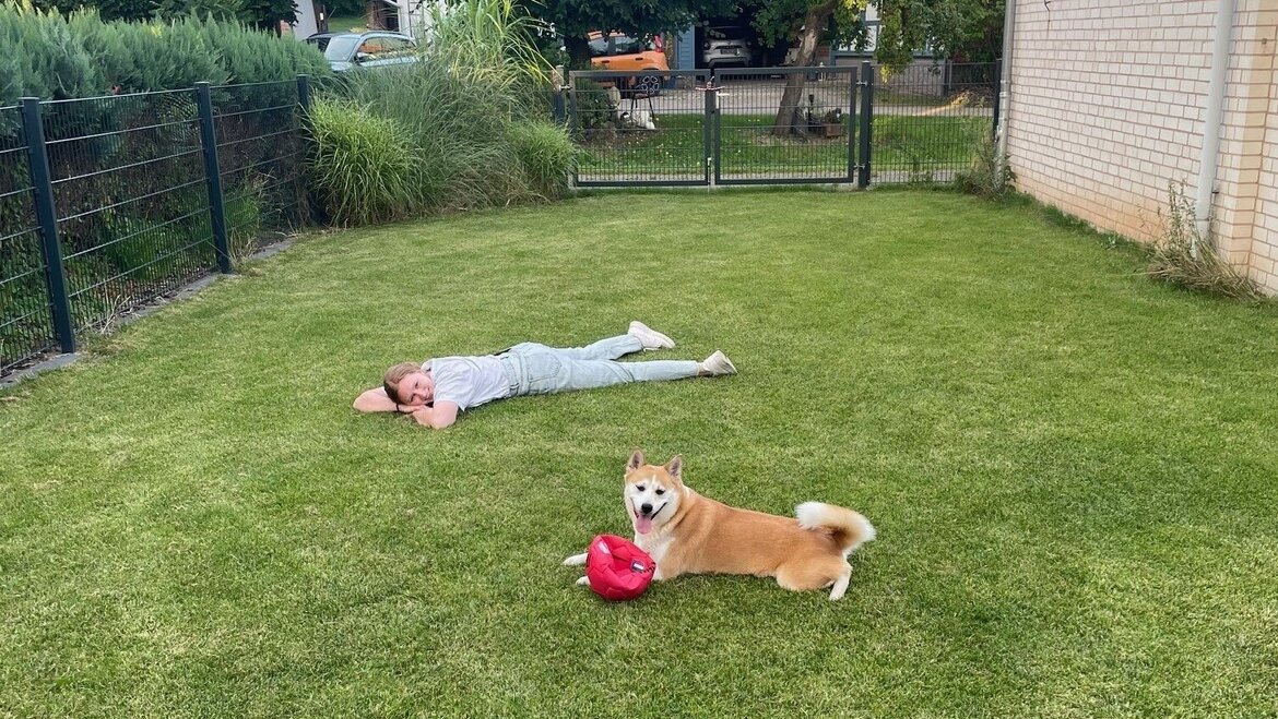 Das Bild zeigt unsere junge Epilepsie-Patientin Lena der Universitätsmedizin Göttingen mit ihrem Hund im Garten. Die beiden liegen auf dem Rasen in der Sonne.