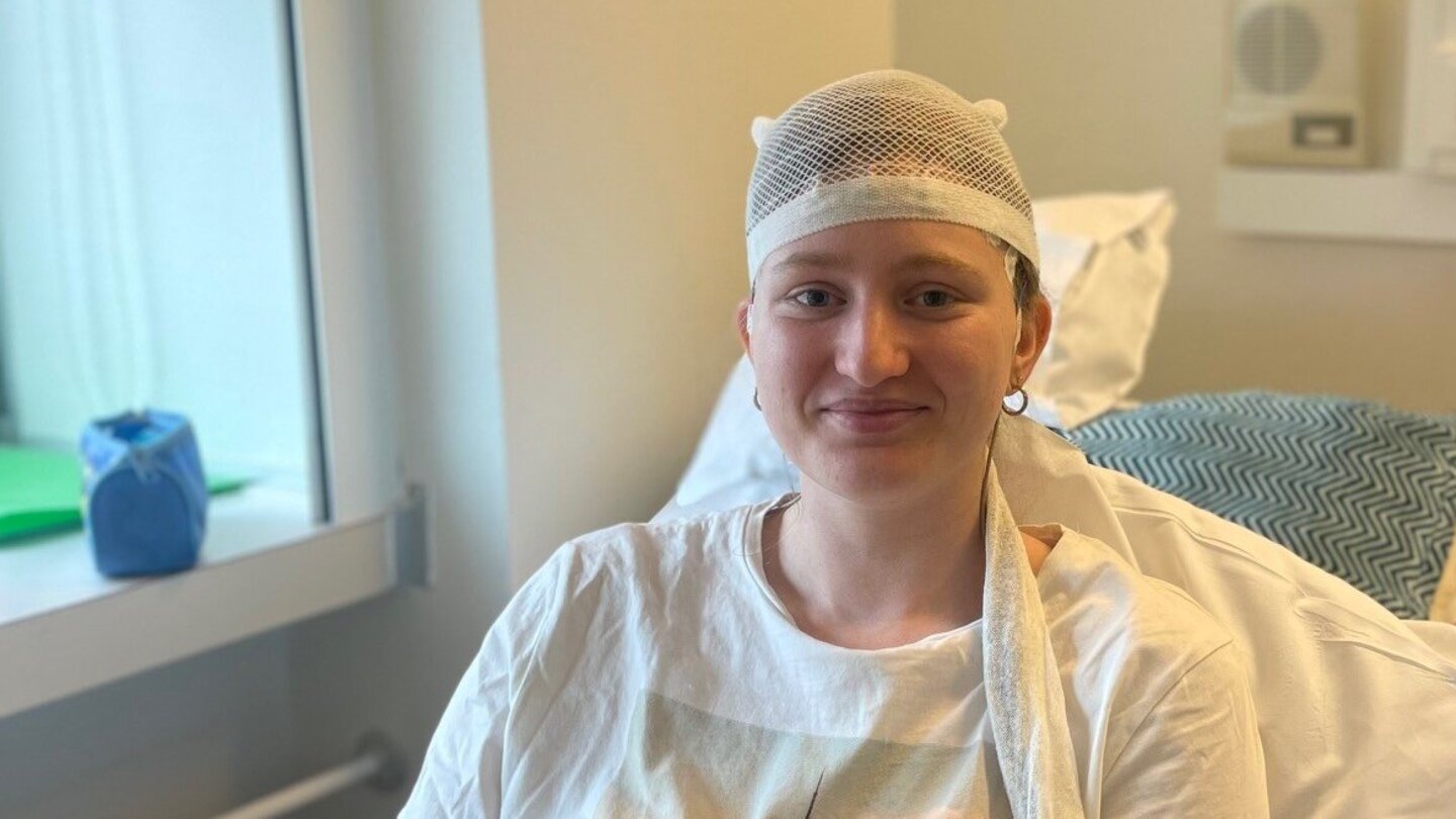Das Bild zeigt die junge Epilepsie-Patientin Lena der Universitätsmedizin Göttingen in einem Patientenzimmer. Sie sitzt mit einem EEG-Helm in ihrem Bett.