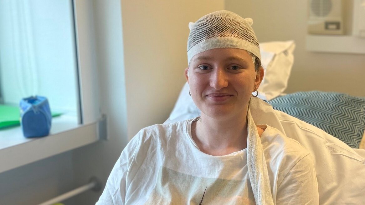 Das Bild zeigt die junge Epilepsie-Patientin Lena der Universitätsmedizin Göttingen in einem Patientenzimmer. Sie sitzt mit einem EEG-Helm in ihrem Bett.