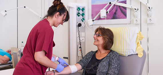 Eine Pflegekraft nimmt einer Patientin Blut ab.